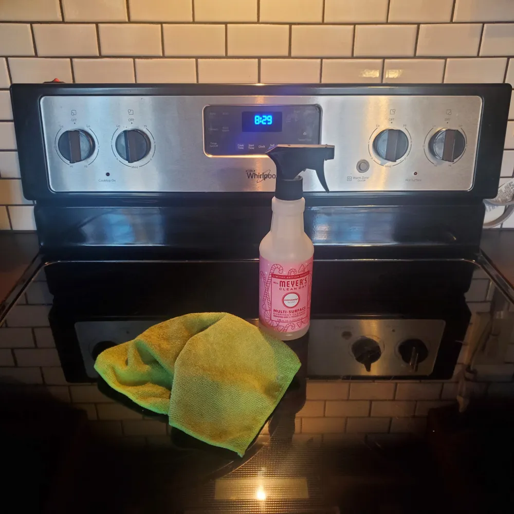 Cleaning a glass cooktop with Mrs. Meyer's multisurface spray.