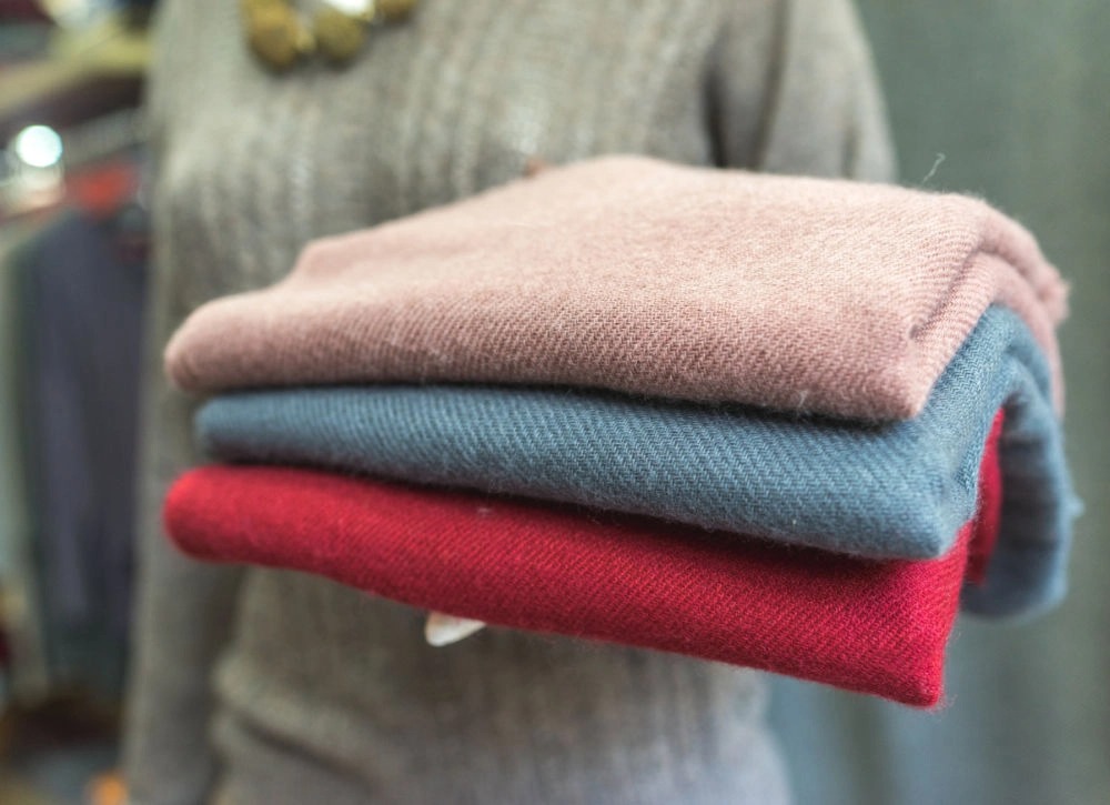 A woman holding a stack of blankets.