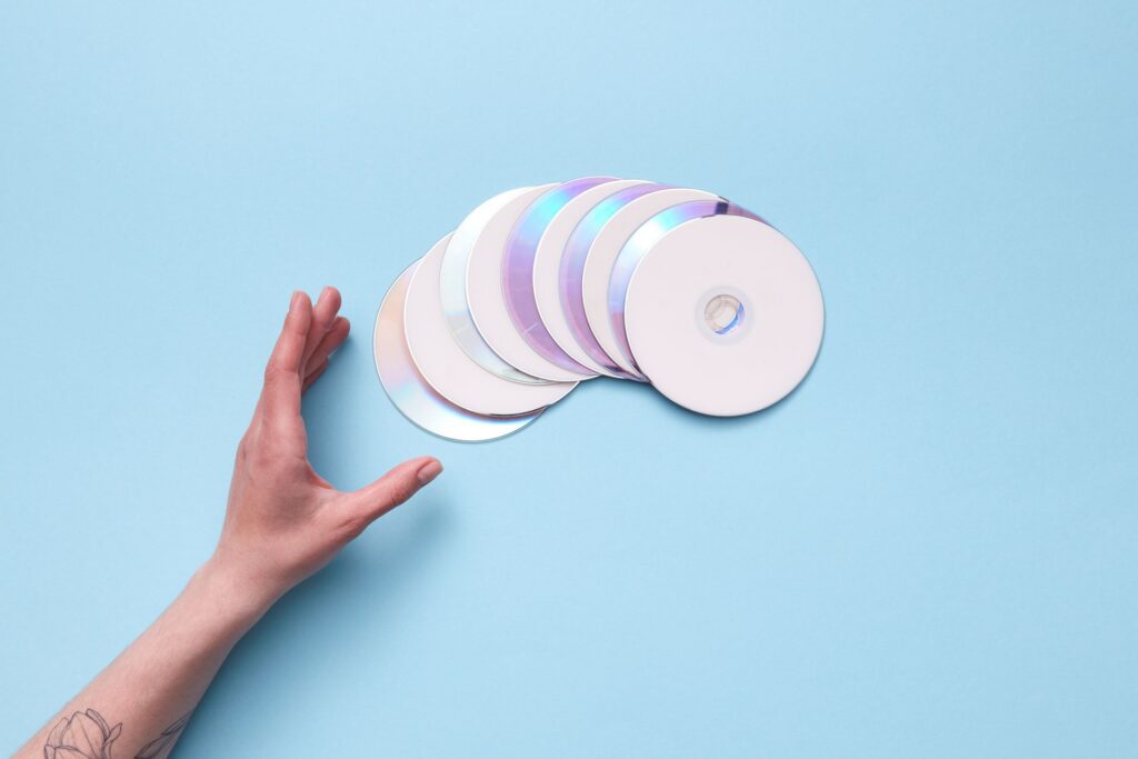 Blue background with a hand reaching for a stack of CDs
